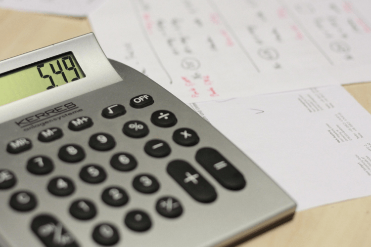 Rekenmachine met bedrag op het display, naast facturen en papieren; beeld bij prijs en verdienmodel voor ondernemers die slimmer geld willen verdienen.