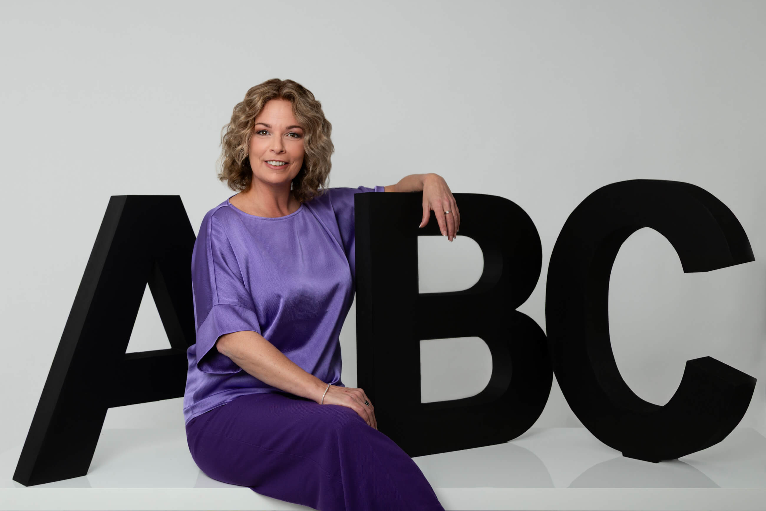 Claudia Bouwens bij grote ABC-letters, beeld bij uitleg van de ABC-methodiek