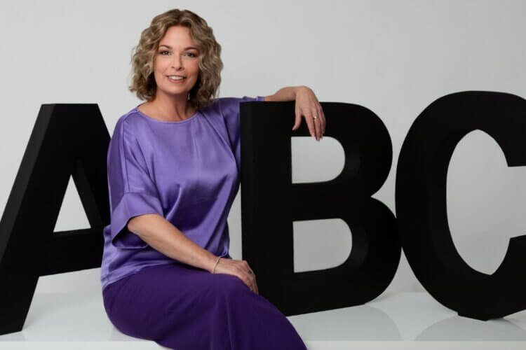 Claudia Bouwens zittend voor grote zwarte ABC-letters als uitnodiging voor een gesprek over HRM support voor het MKB