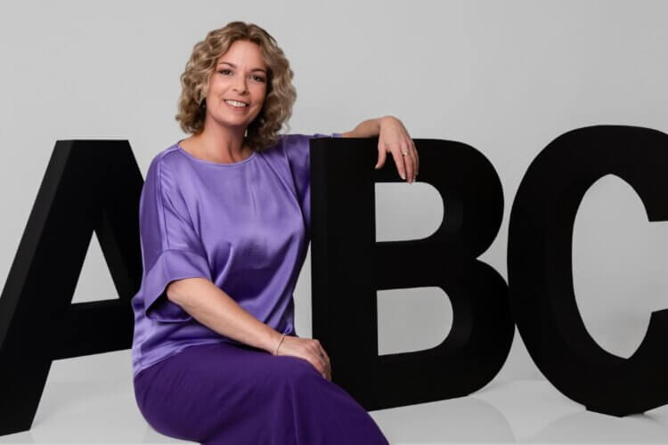 Claudia Bouwens leunend tegen grote zwarte ABC-letters als uitnodiging voor een inspiratiesessie