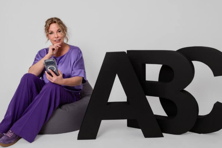 Claudia Bouwens zittend naast grote ABC-letters als uitnodiging voor een gesprek over verandertrajecten
